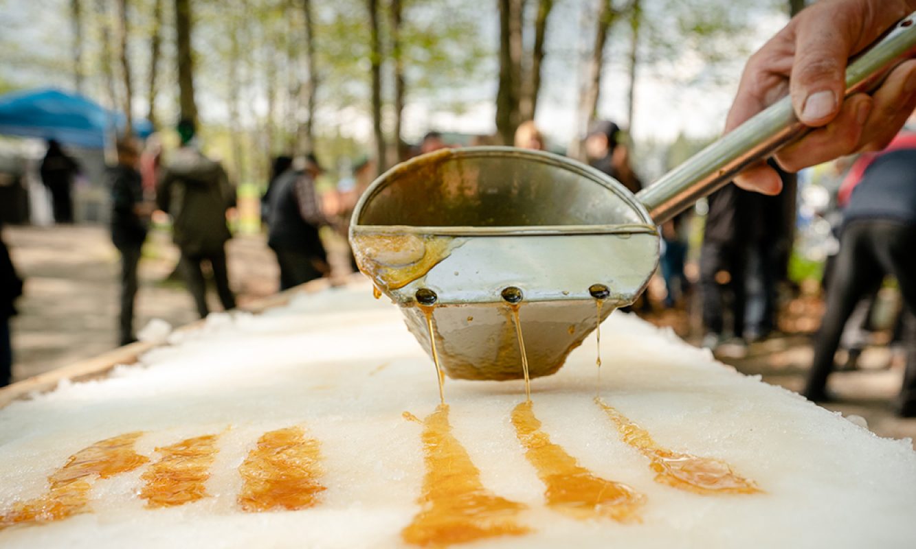 Louche qui étend de la tire d'érable sur la neige pendant la partie de sucre du Festival des Sucres de Saint-Pierre-Baptiste