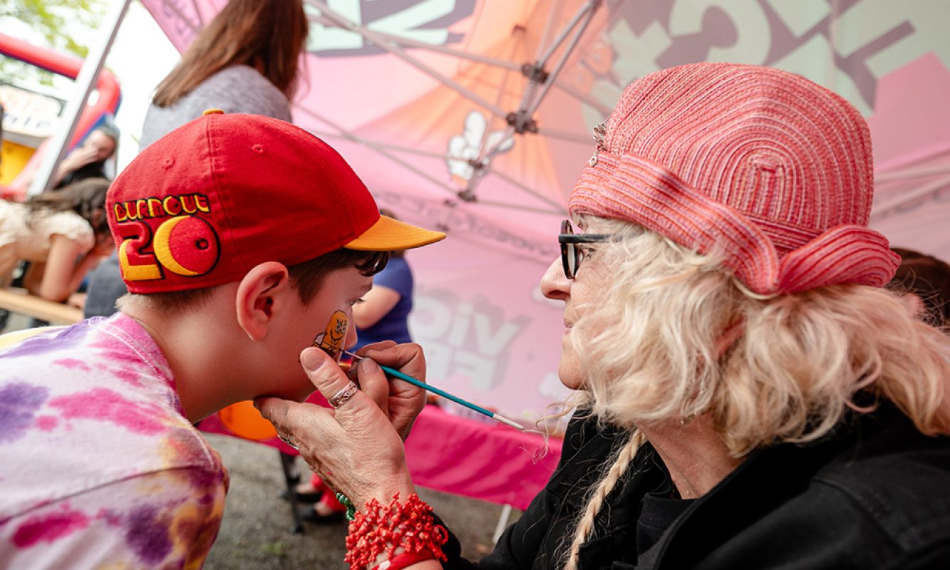 Une dame maquille un jeune enfant pendant les activités familiales du Festival des Sucres de Saint-Pierre-Baptiste