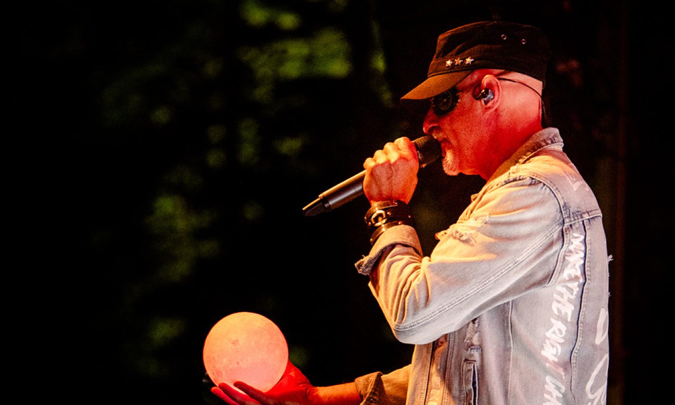 Un chanteur qui tient une sphère blanche pendant son spectacle au festival RockFest de Saint-Pierre-Baptiste