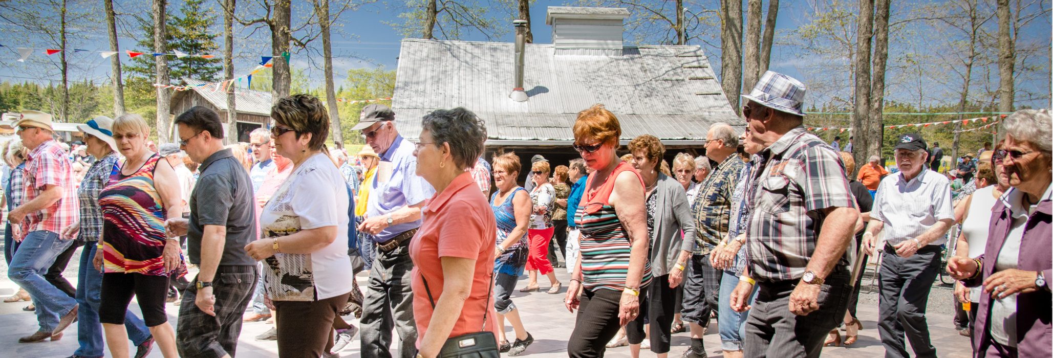 Un groupe de festivaliers s'adonne à la danse en ligne en pleine forêt lors du Festival des Sucres de Saint-Pierre-Baptiste