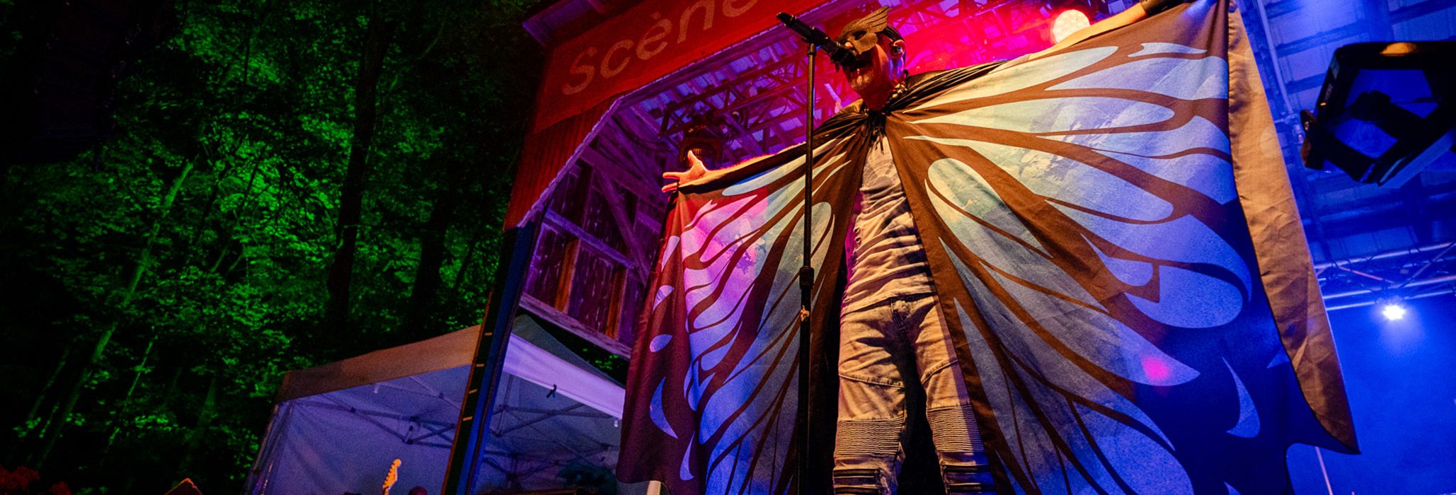 Un artiste avec des ailes de papillon est sur la scène du festival RockFest de St-Pierre-Baptiste